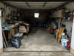 Überfüllte Garage mit Werkzeugen, Kartons und Sperrmüll vor der Räumung.
